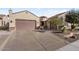 Tan house with brown garage door, stone accents, and nicely landscaped yard at 26822 W Oraibi Dr, Buckeye, AZ 85396