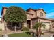 Two-story house with beige exterior, stone accents, and a three-car garage at 10746 W Desert Elm Ln, Peoria, AZ 85383