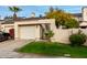 Tan stucco townhouse with a white garage door, landscaping, and gated entry at 3314 E Kelton Ln # 104, Phoenix, AZ 85032