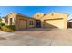 Tan colored house with a three-car garage and brick driveway at 10220 E Thatcher Ave, Mesa, AZ 85212