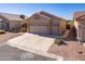 Tan house with a two car garage and desert landscaping at 11553 W Sonoran Ct, Surprise, AZ 85378