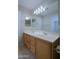 Double vanity bathroom with wood cabinets and updated lighting at 4047 E Rowel Rd, Phoenix, AZ 85050