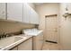 Bright laundry room with washer, dryer, cabinets, and utility sink at 7979 E Evening Glow Dr, Scottsdale, AZ 85266
