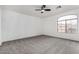 Bright bedroom with grey carpet, ceiling fan, and large window at 23957 W Tonto St, Buckeye, AZ 85326