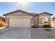 Tan one-story house with a two-car garage and landscaping at 43741 W Rio Grande Dr, Maricopa, AZ 85138