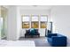 Bright bedroom with three windows, gray upholstered bench, and blue accent chair at 562 N Sun Rd, Apache Junction, AZ 85119