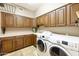 Laundry room with washer, dryer and wooden cabinets at 8689 E Windrose Dr, Scottsdale, AZ 85260