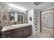 Modern bathroom with double vanity, stone tile, and view to entryway at 3044 W Desert Cove Ave, Phoenix, AZ 85029