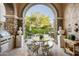 Outdoor kitchen and dining area with arched entry and stone details at 19501 N 101St St, Scottsdale, AZ 85255