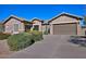 Tan colored house with a two-car garage and well-manicured landscaping at 7132 W Trenton Way, Florence, AZ 85132