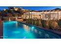 Inviting pool with lighting and mountain views at night at 4796 E Charles Dr, Paradise Valley, AZ 85253