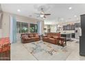 Open living area with leather sofas, large windows, and a ceiling fan at 42833 W Mallard Rd, Maricopa, AZ 85138
