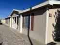 Exterior view of a beige manufactured home with red shutters and a covered porch at 437 E Germann Rd # 158, San Tan Valley, AZ 85140