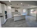 Modern kitchen featuring white cabinets, an island, and tile flooring at 17463 N 66Th Ave, Glendale, AZ 85308