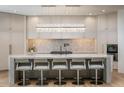 Modern kitchen features a large island with seating, marble countertops, and a statement light fixture at 28145 N 91St St, Scottsdale, AZ 85262