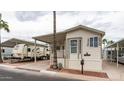 Mobile home with covered porch, RV parking, and desert landscaping at 412 Hawks Eye Dr, Apache Junction, AZ 85119