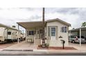 Mobile home with covered porch, RV parking, and desert landscaping at 412 Hawks Eye Dr, Apache Junction, AZ 85119