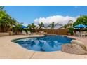 Inviting freeform pool with large rocks and patio seating at 6963 W Aurora Dr, Glendale, AZ 85308