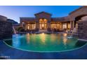 Inviting pool and spa with beautiful landscaping at night at 11475 E Paradise Ln, Scottsdale, AZ 85255