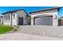 Modern home's exterior boasts a gray garage door and manicured lawn at 5656 E Star Valley St, Mesa, AZ 85215