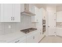 Modern kitchen with white cabinets, gas cooktop, and double oven at 20230 W Hollyhock St, Buckeye, AZ 85396