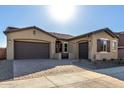 Front exterior of a single-story home with a two-car garage, stucco exterior, and landscaping at 21673 E Roundup Way, Queen Creek, AZ 85142