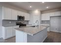 Modern kitchen with white cabinets, granite island, and stainless steel appliances at 40060 W Bravo Dr, Maricopa, AZ 85138