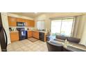 Eat-in kitchen with wood cabinets, black appliances, and access to backyard at 12413 N El Frio St, El Mirage, AZ 85335