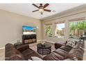 Living room with leather sectional sofa, coffee table, and large windows at 12903 W Brookhart Way, Peoria, AZ 85383