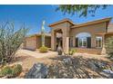 Tan house with a two-car garage, arched entryway, and desert landscaping at 9768 E Balancing Rock Rd, Scottsdale, AZ 85262