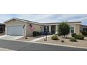 Tan single-story home with attached garage, landscaped yard, and American flag at 3301 S Goldfield Rd # 6044, Apache Junction, AZ 85119