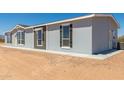 House exterior view, showing light gray siding, windows, and a small backyard at 900 N Windy Meadow Ln, Maricopa, AZ 85139