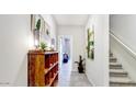 Bright hallway with tile floors, wooden shelving unit, and modern wall art at 7577 W Darrow St, Laveen, AZ 85339