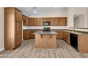 Kitchen with an island, wood cabinets, and light-colored laminate flooring at 42054 W Cheyenne Dr, Maricopa, AZ 85138