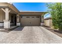 Two-car garage with paver driveway and landscaping at 14634 W Wethersfield Rd, Surprise, AZ 85379