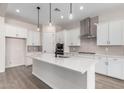 Modern white kitchen with a large island, stainless steel appliances, and pendant lighting at 16348 W Avenida Del Sol --, Surprise, AZ 85387