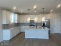 Modern kitchen with island, stainless steel appliances, and white cabinetry at 11522 S 50Th Ln, Laveen, AZ 85339