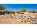 House with a rock wall and mature trees at 16738 E Lone Mountain Rd, Scottsdale, AZ 85262