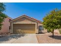 Tan stucco house with a double-car garage and a small, landscaped front yard at 23780 W Tonto St, Buckeye, AZ 85326