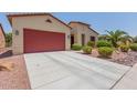 Front view of a house with red garage door and desert landscaping at 20285 N Winter Escape Ct, Maricopa, AZ 85138
