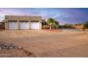 Three-car garage with white doors and desert landscaping at 19950 W Cambridge Ave, Buckeye, AZ 85396