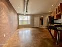 Open living area with exposed brick wall, polished concrete floors, and large window at 1701 E Colter St # 141, Phoenix, AZ 85016