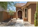 Inviting entryway with a dark brown door and desert plants at 17555 W Dalea Dr, Goodyear, AZ 85338
