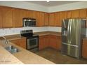 Kitchen with stainless steel appliances and wood cabinets at 43624 W Bailey Dr, Maricopa, AZ 85138