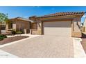 Front view of a beige house with a large garage and brick driveway at 26496 W Lone Cactus Dr, Buckeye, AZ 85396
