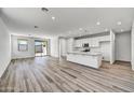 Open-concept living room and kitchen with wood-look floors at 37535 W Patterson St, Maricopa, AZ 85138