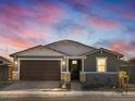 Single-story home with gray exterior, brown garage door, and stone accents at dusk at 4657 N 177Th Ln, Goodyear, AZ 85395