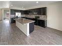 Modern kitchen with dark cabinets, granite island, and tile flooring at 2178 N 212Th Ln, Buckeye, AZ 85396