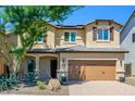 Two-story house with tan siding, brown garage door, and landscaping at 1860 W Buckhorn Trl, Phoenix, AZ 85085