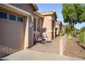 Side view of a tan house with a two-car garage and seating area at 42531 W Heavenly Pl, Maricopa, AZ 85138